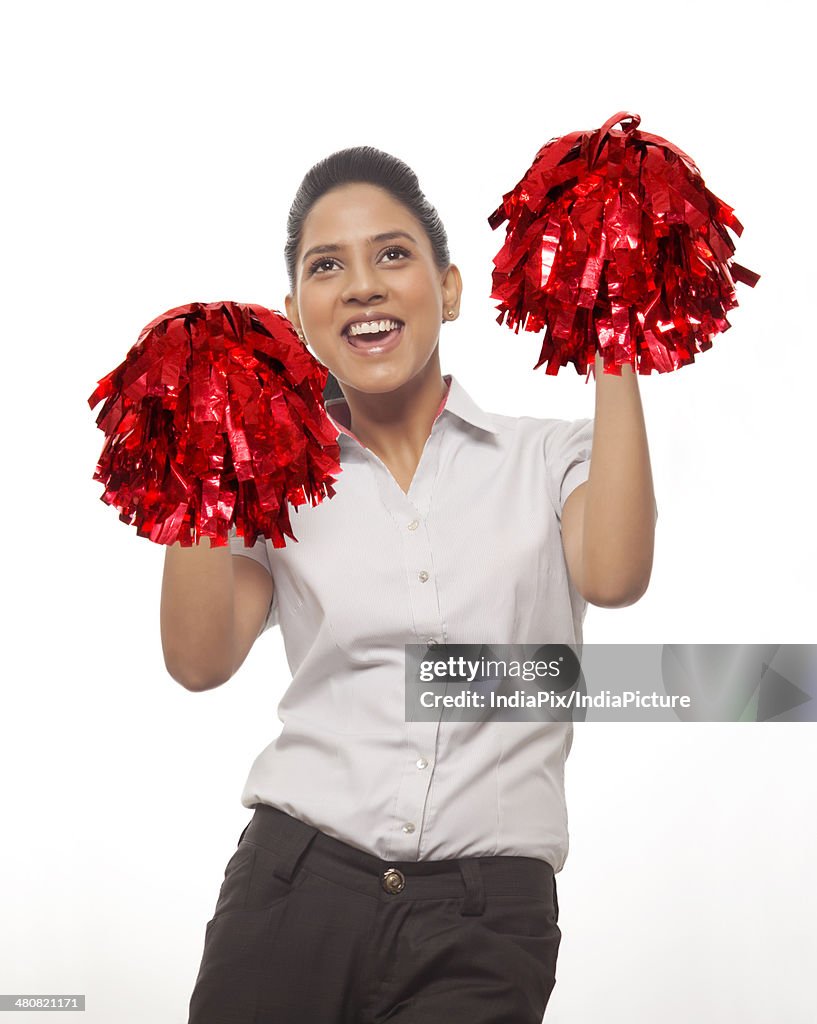 Happy businesswoman cheering with pompoms against white background