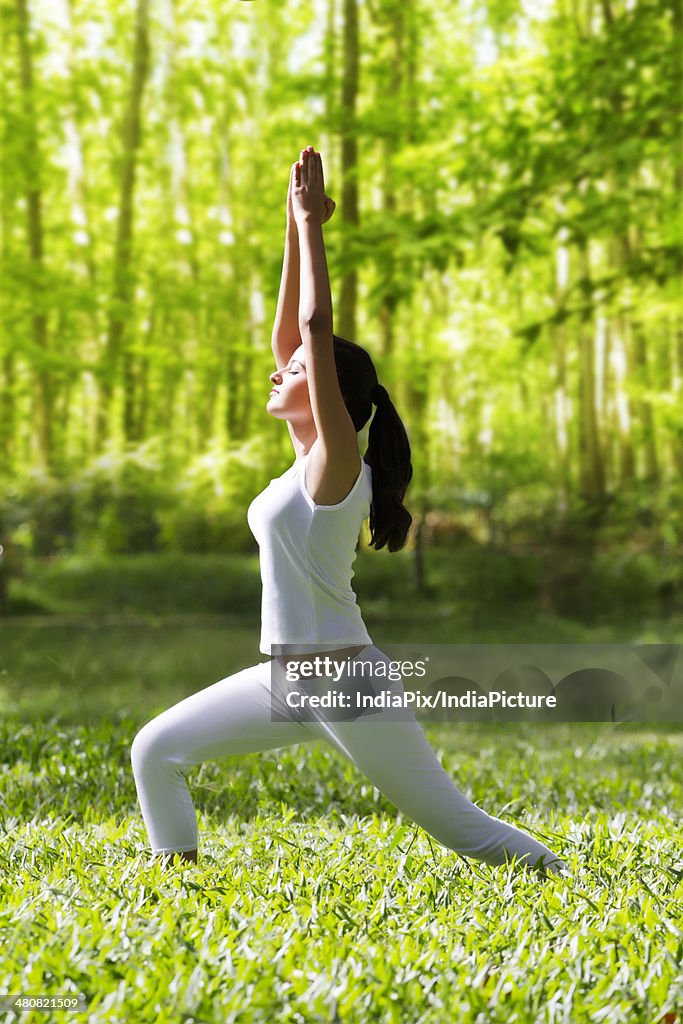 Side view of woman with hands clasped doing stretching exercise in park