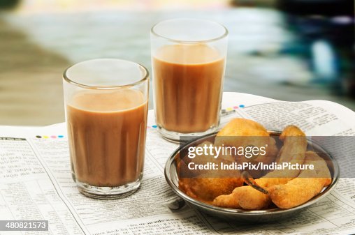 Close-up of morning chai with bhajiyas and vada on newspaper Close-up of morning chai with bhajiyas and vada on newspaper