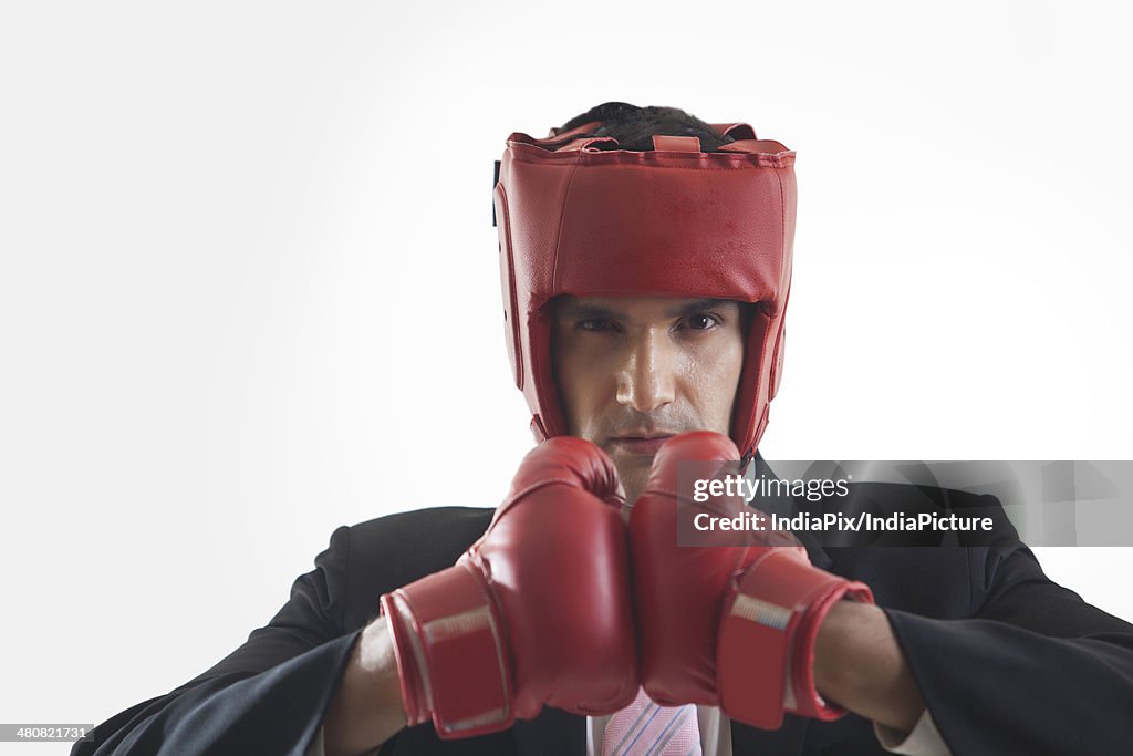 Portrait of aggressive businessman with red boxing gloves over white background