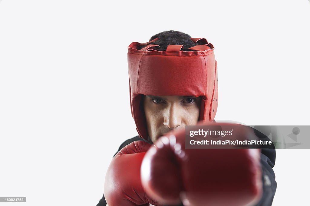 Portrait of businessman wearing boxing gloves punching over white background