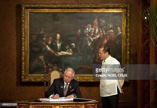Philippine President Benigno Aquino stands beside Malaysian Prime Minister Najib Razak as he signs the guesst book at Malacanang palace in Manila on...