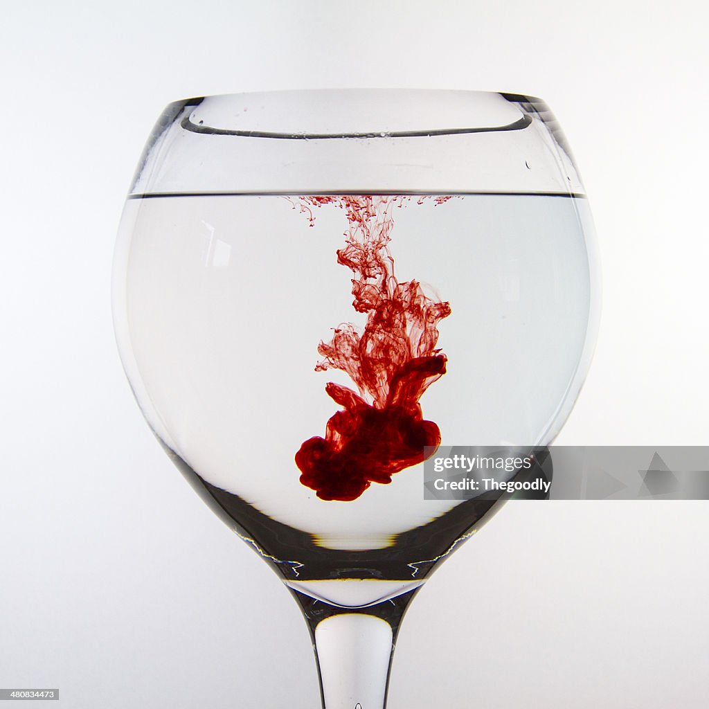 Red ink dissolving in glass of water