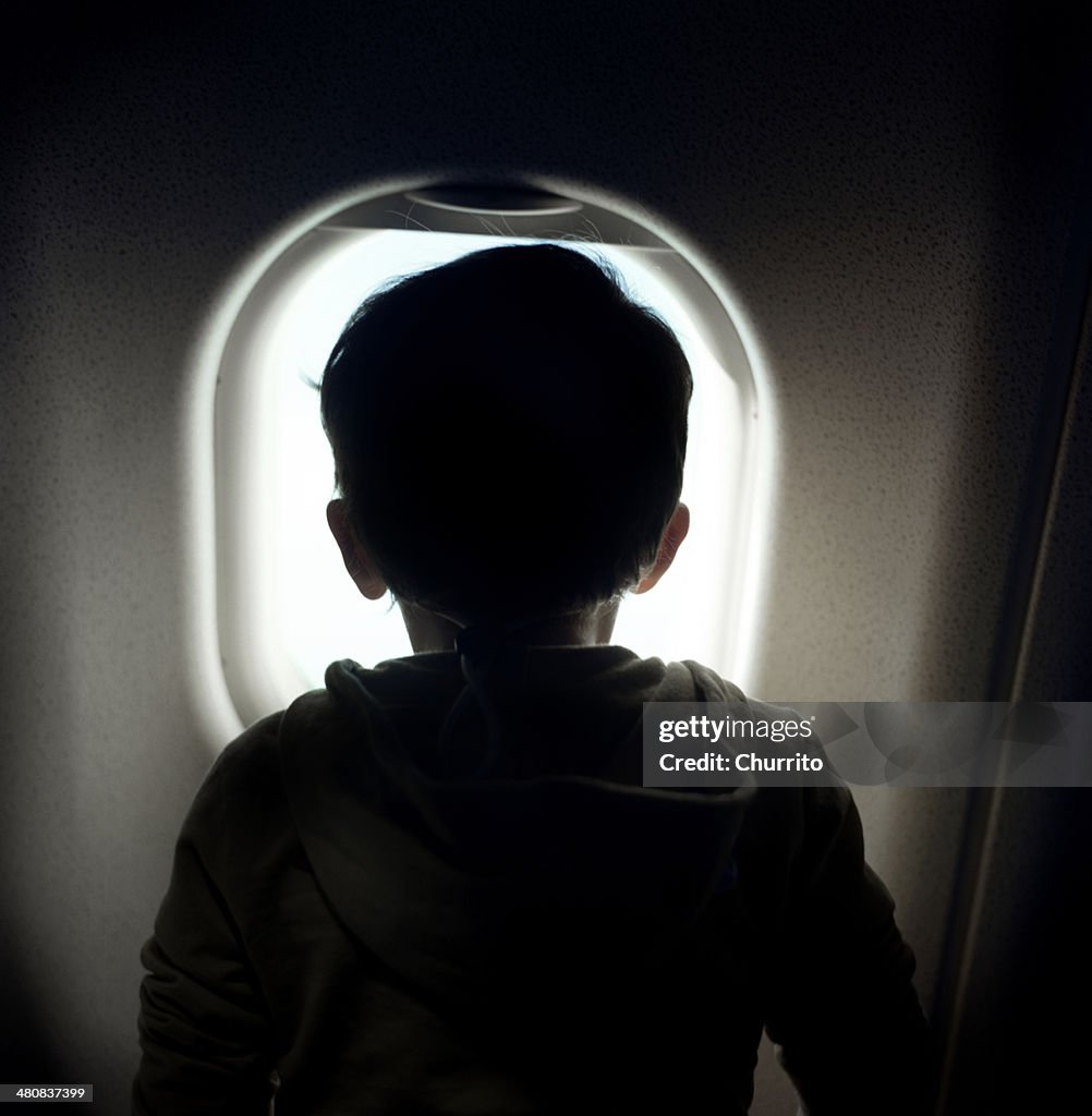 Boy looking through window on airplane