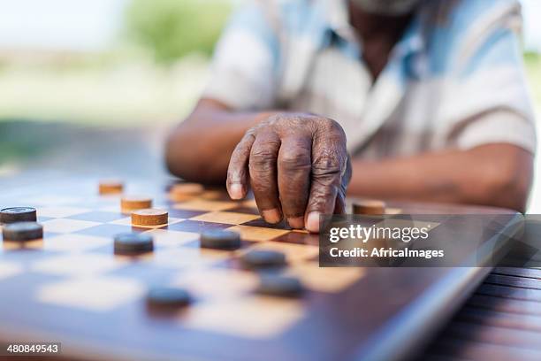 african senior playing chess, making a move - playing chess stockfoto's en -beelden