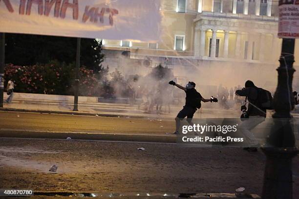 Protester throws a molotov cocktail towards the riot police at the anti-austerity protest in Athens. Molotov cocktails, tear gas and stun grandees...