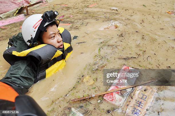 This picture taken on July 15, 2015 shows a rescuer making his way through floodwaters after heavy rainfall hit the area in Songtao county in...