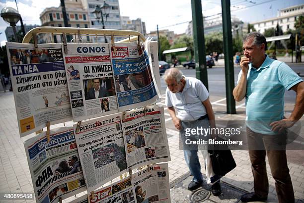 Pedestrians stop to read the newspaper headlines outside a magazine kiosk in central Athens, Greece, on Thursday, July 16, 2015. While Greek...