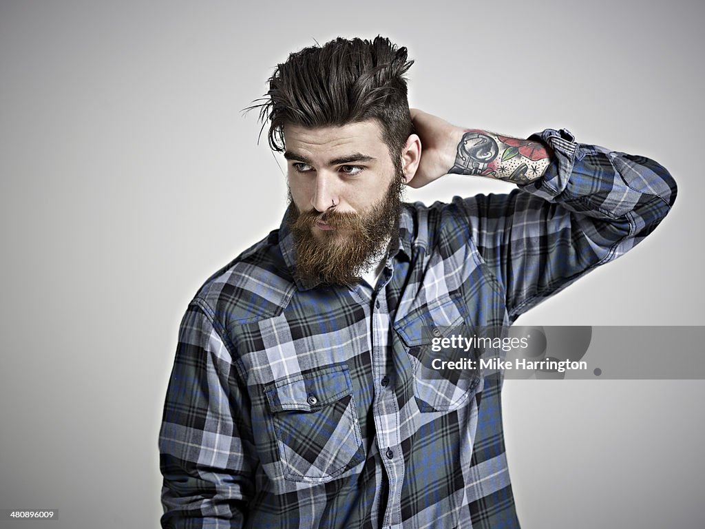 Portrait of man with beard, tattoos & check shirt.