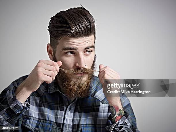 portrait of young man twisting his moustache. - mustache stock-fotos und bilder