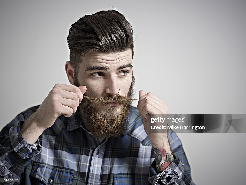 Portrait of young man twisting his moustache.
