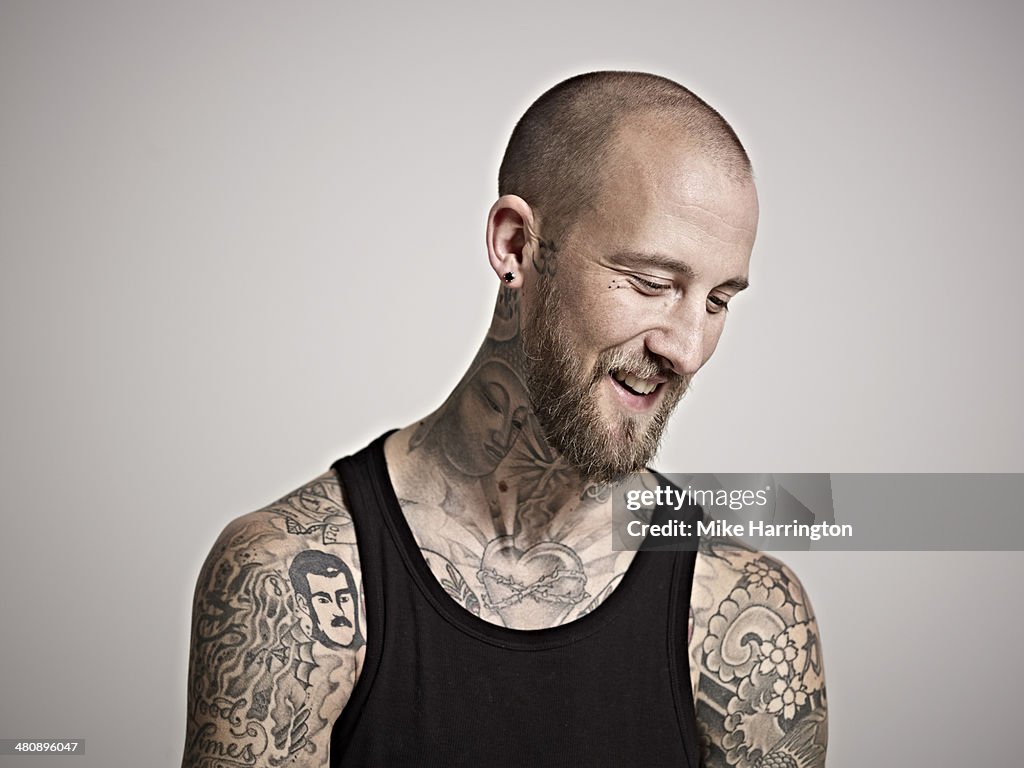 Portrait of heavily tattooed bearded male smiling.