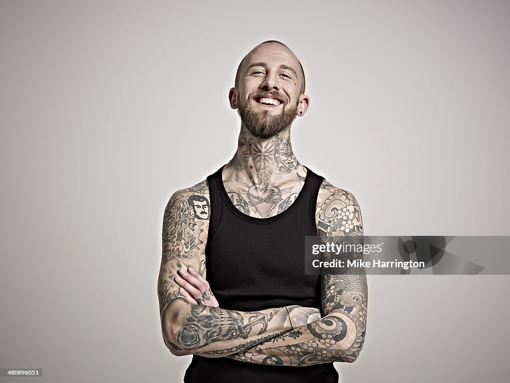 Portrait of bearded man with tattoos laughing.
