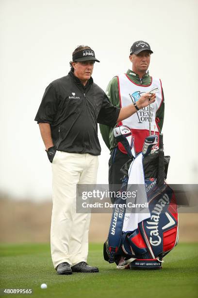 Phil Mickelson talks with his caddy Jim Mackay on the 10th during Round One of the Valero Texas Open at the AT&T Oaks Course on March 27, 2014 in San...