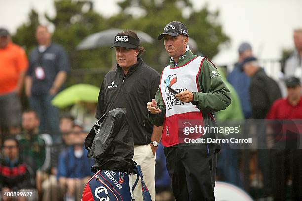 Phil Mickelson talks with his caddy Jim Mackay on the 10th during Round One of the Valero Texas Open at the AT&T Oaks Course on March 27, 2014 in San...