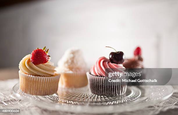 Berlin, Germany Four cupcakes with a cherry and a strawberry a raspberry on a plate on July 15, 2015 in Berlin, Germany.
