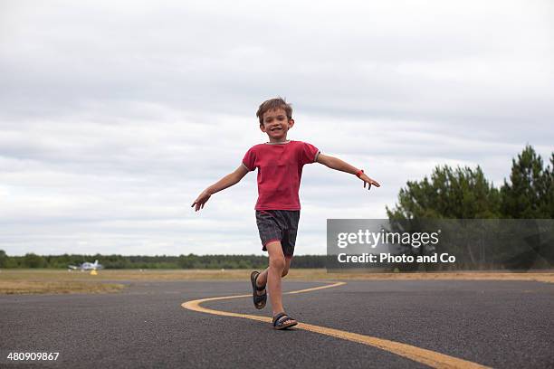 child running on asphalt - les bras écartés photos et images de collection