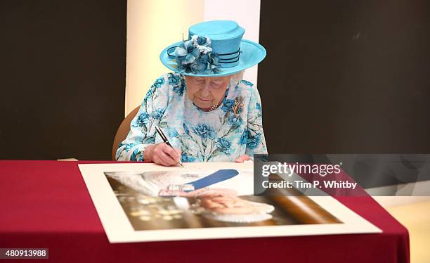 Queen Elizabeth II signing a portrait of herself at the Broadway Theatre on July 16, 2015 in Barking, United Kingdom.