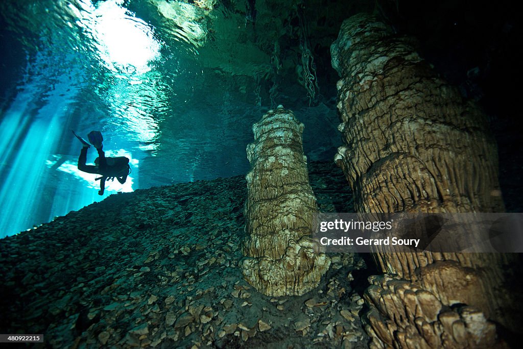 Diver swimming among stalagmites