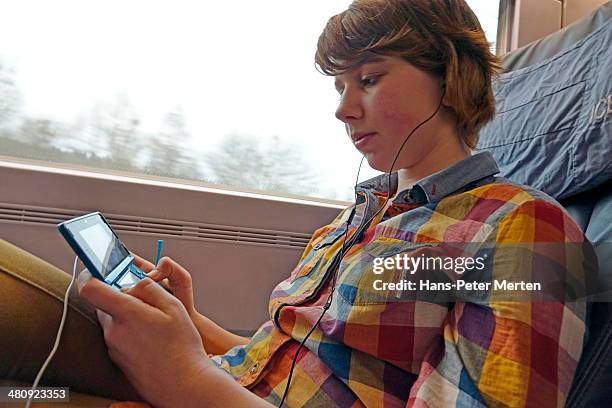 girl playing with nitendo in train - game console stockfoto's en -beelden