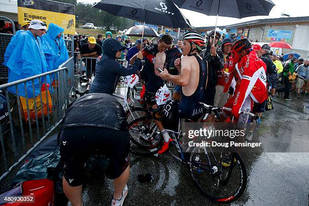 Riders shelter under umbrellas after completing stage twelve of the 2015 Tour de France, a 195 km stage between Lannemezan and Plateau de Beille, on...