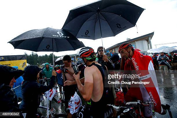 Riders shelter under umbrellas after completing stage twelve of the 2015 Tour de France, a 195 km stage between Lannemezan and Plateau de Beille, on...
