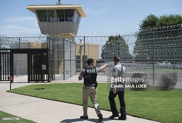 Police and a prison guard patrol the entrance of the El Reno Federal Correctional Institution in El Reno, Oklahoma, July 16 during a visit by US...
