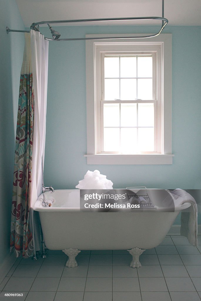 Bathroom with clawfoot tub filled with bubbles.