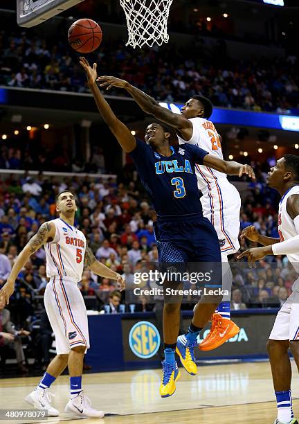 Jordan Adams of the UCLA Bruins goes to the basket as Casey Prather of the Florida Gators defends during a regional semifinal of the 2014 NCAA Men's...