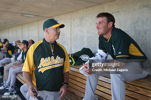 Pitching Coach Curt Young of the Oakland Athletics talks with Philip Humber in the dugout a spring training game against the Milwaukee Brewers at...