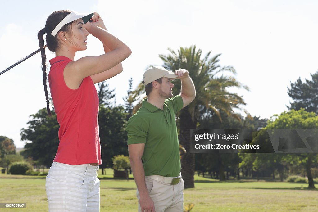 Young female practicing golf with trainer