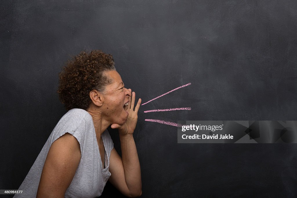 Senior woman in front of blackboard pretending to shout