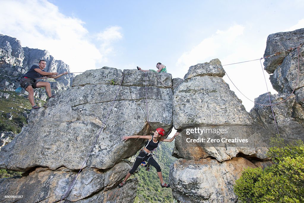 Three rock climbers climbing up rock formation