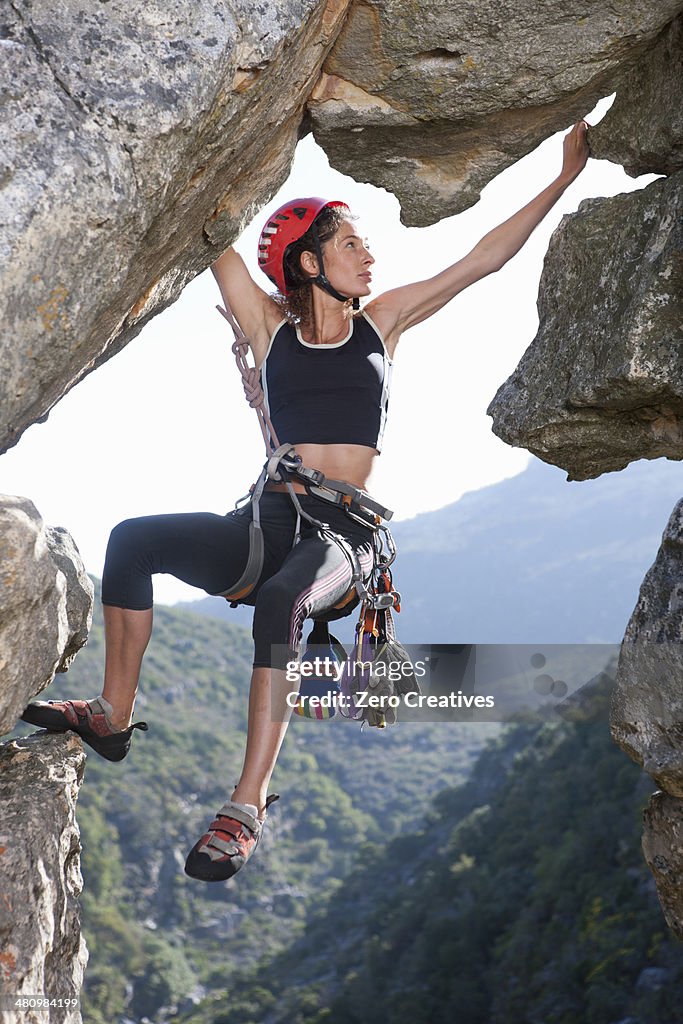 Young female rock climber balancing on rock face