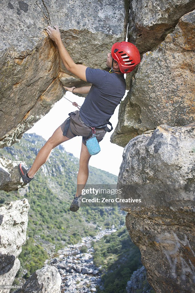 Young male rock climber balancing and holding rope