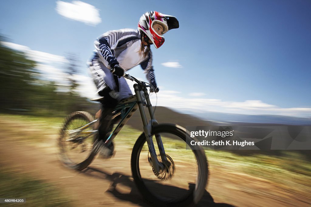 Female mountain biker speeding down dirt track