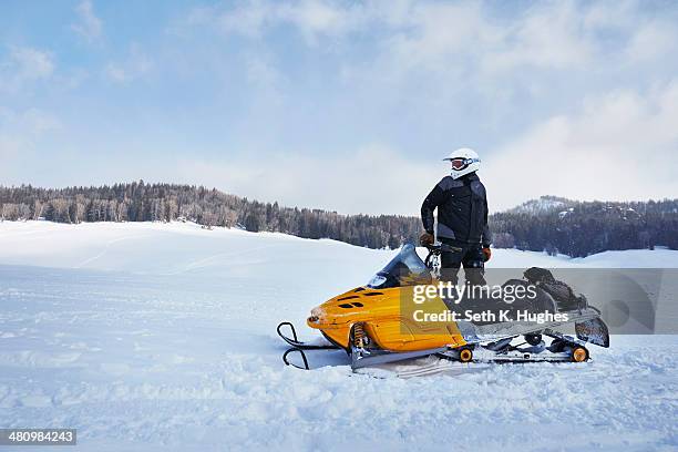 mid adult man on snowmobile, togwotee pass, wyoming, usa - snowmobiling stock-fotos und bilder