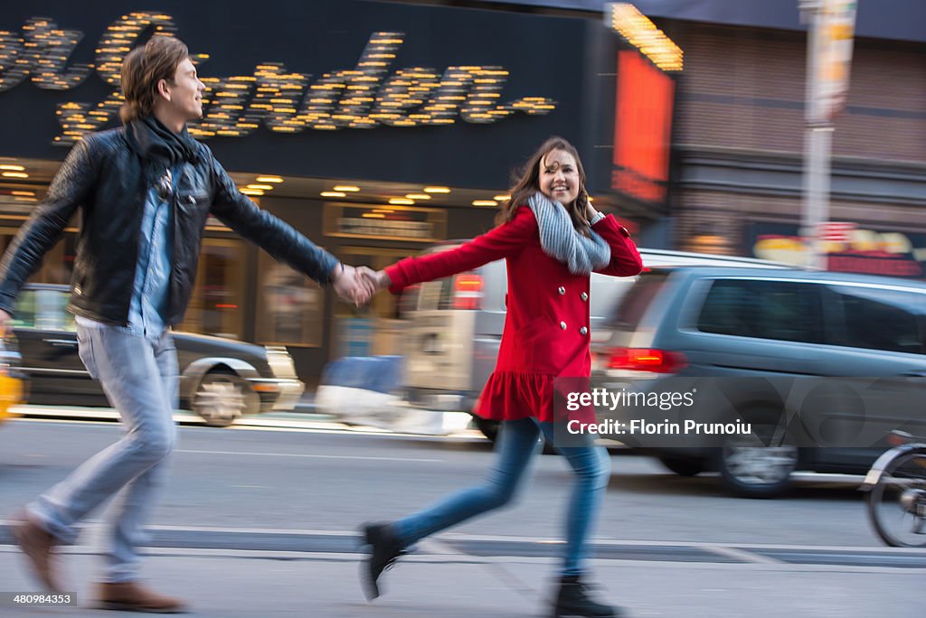 Young couple running along street, New York City, USA