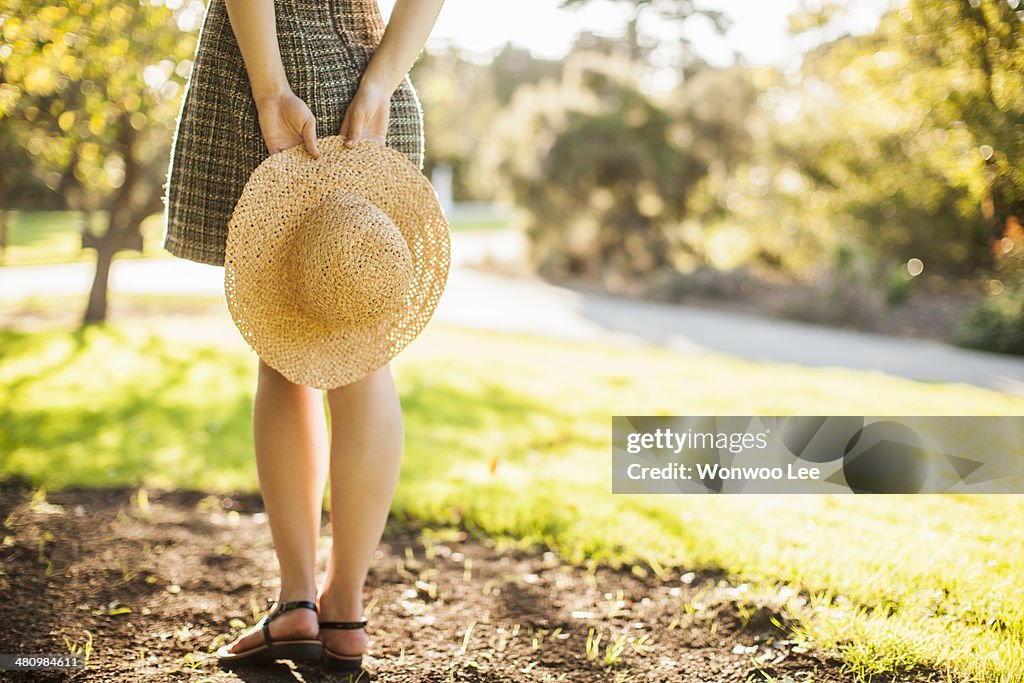 Cropped image of teenage girl holding sunhat behind her back