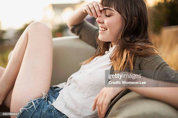 young woman reclining on seat outdoors - summer cardigan women stockfoto's en -beelden