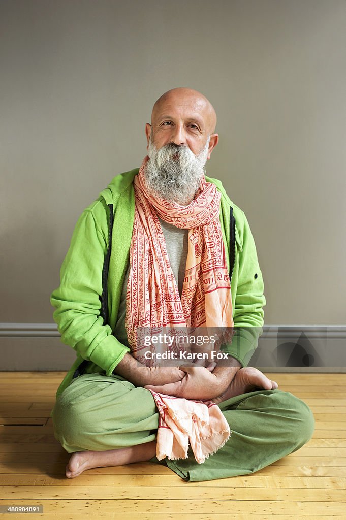 Portrait of mature man sitting in lotus pose on floor