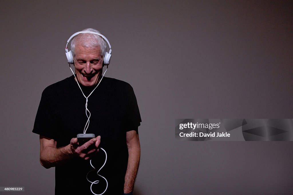 Portrait of senior man wearing headphones and using MP3 player