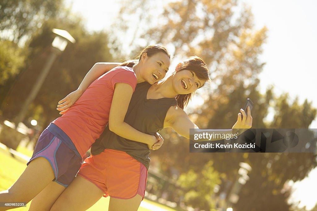 Two young women taking self portrait in park