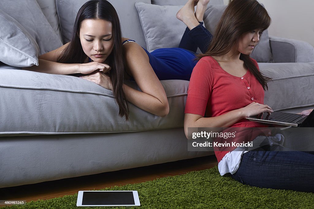 Two young women in sitting room with digital tablets