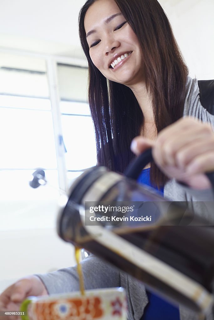 Young woman in kitchen pouring coffee