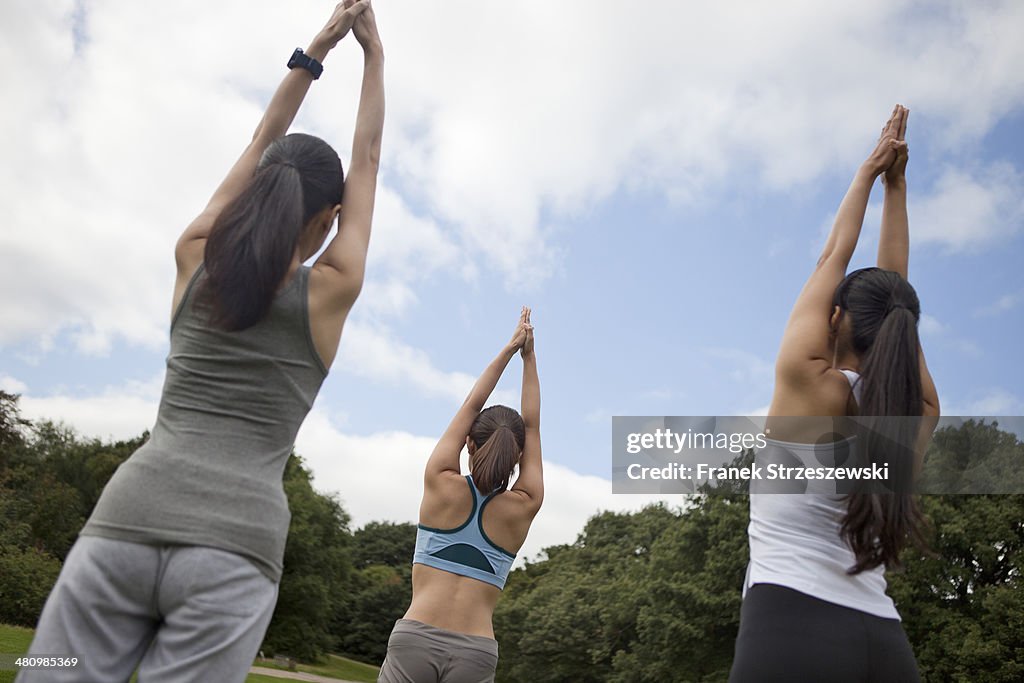 Three young women practicing yoga in park