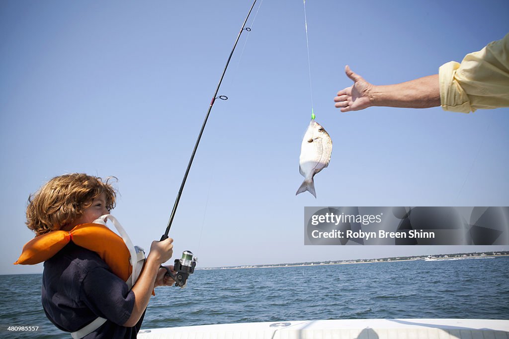 Boy reeling in fish on boat, Falmouth, Massachusetts, USA