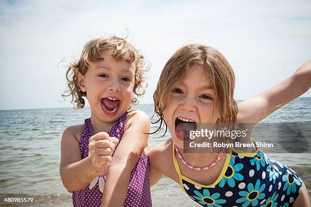 portrait of two sisters pulling faces on beach at falmouth, massachusetts, usa - sólo niñas fotograf�ías e imágenes de stock