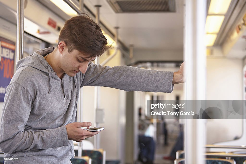 Mid adult man using cellphone on subway train