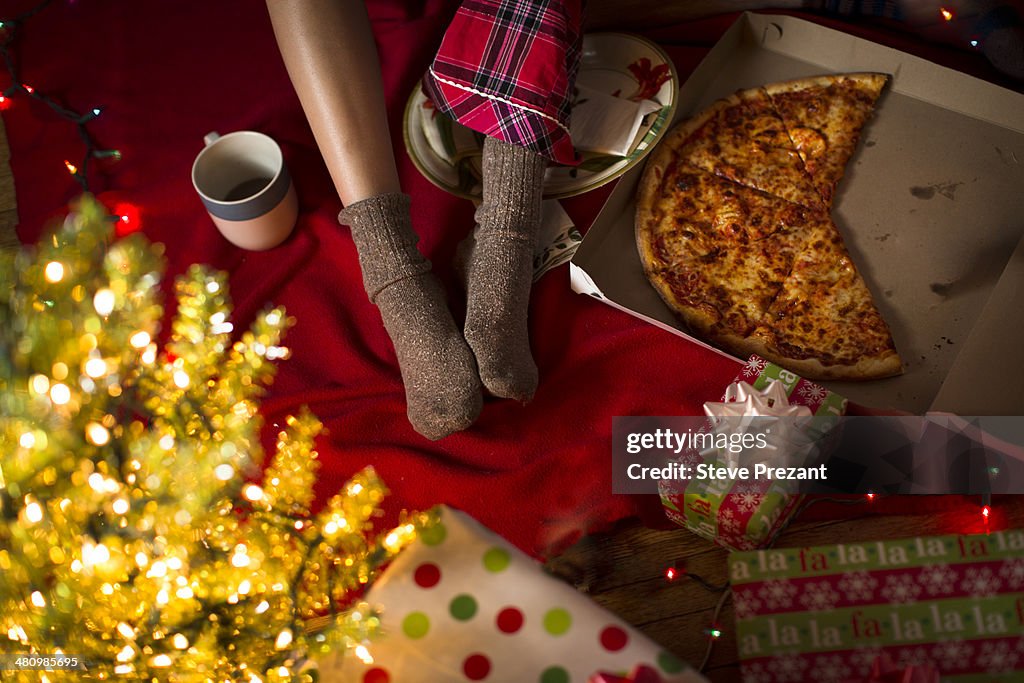 Young woman's legs amongst christmas gifts and pizza box